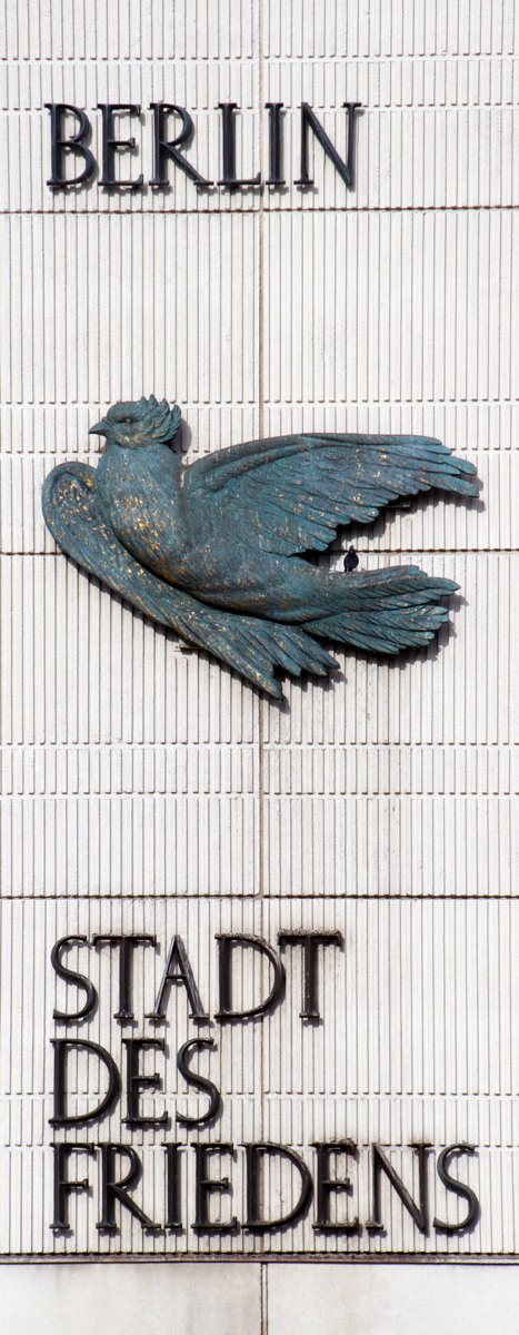 Fassade mit Relief-Plastik einer Friedenstaube, auf der eine lebendige Taube sitzt, und der Schrift "Berlin – Stadt des Friedens"